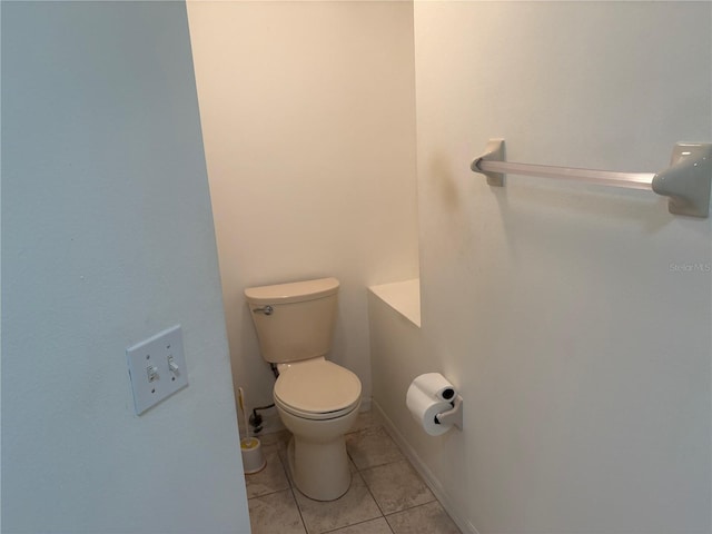 half bath featuring baseboards, toilet, and tile patterned floors