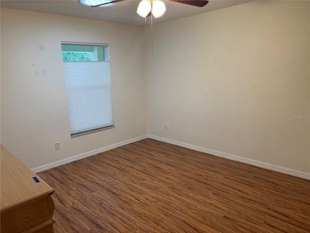 unfurnished room with a ceiling fan, dark wood-style flooring, and baseboards