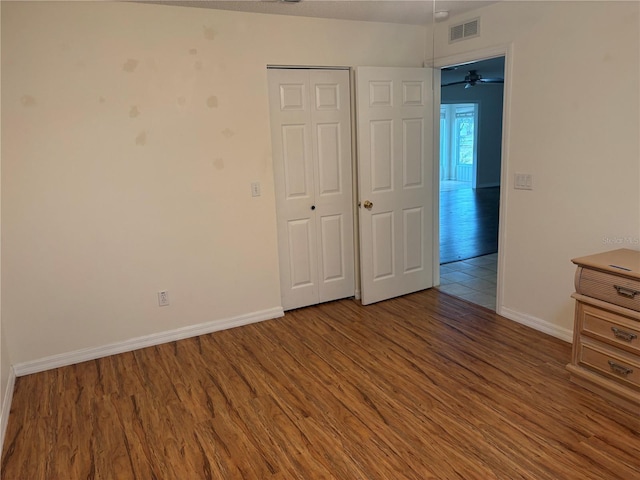 unfurnished bedroom featuring a closet, visible vents, baseboards, and wood finished floors