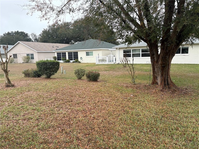 rear view of property featuring stucco siding and a yard