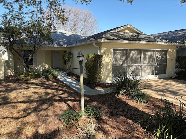 view of front of property featuring a shingled roof, driveway, an attached garage, and stucco siding