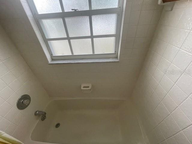 bathroom with a healthy amount of sunlight and tiled shower / bath combo