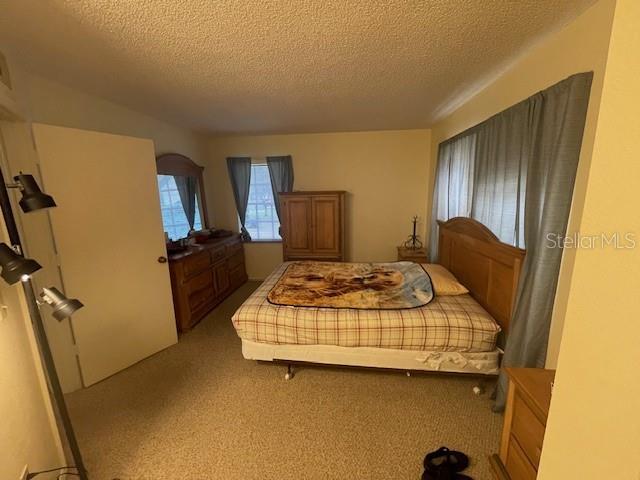 bedroom with a textured ceiling and light colored carpet