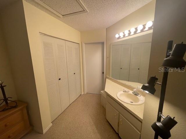 7945 Midway Drive Ter Unit H201, Ocala, FL 34472 - bathroom with a closet, vanity, a textured ceiling, and carpet flooring