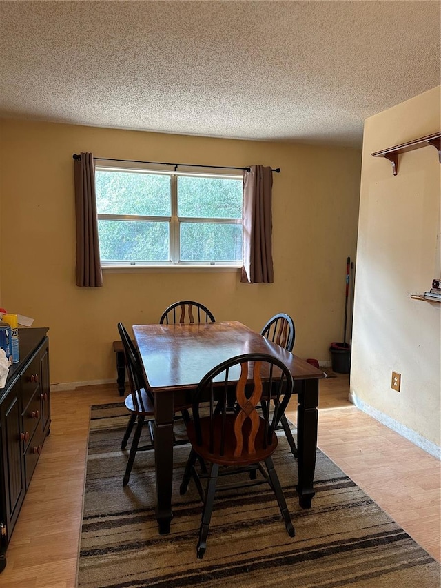 dining area featuring light hardwood / wood-style floors and a textured ceiling