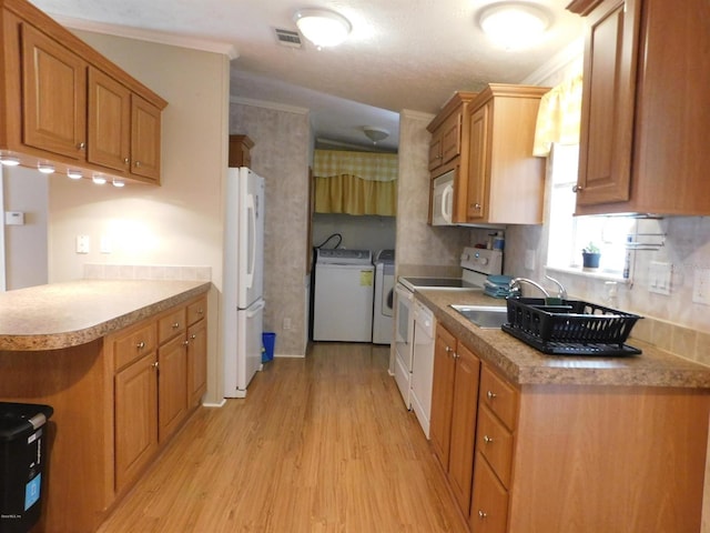 kitchen with sink, crown molding, light hardwood / wood-style floors, white appliances, and washer and clothes dryer