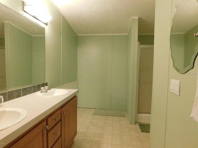 bathroom with a textured ceiling, vanity, a shower with door, and ornamental molding