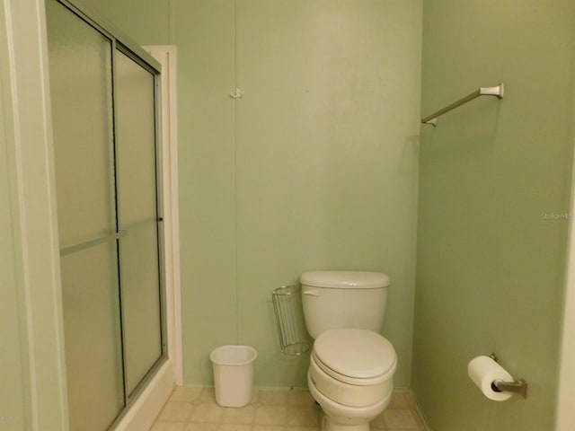 bathroom featuring a shower with door and toilet