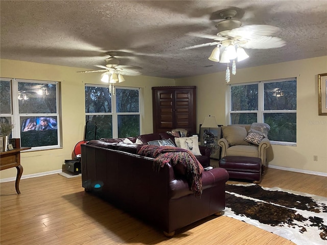 living room with ceiling fan, a textured ceiling, and light wood-type flooring