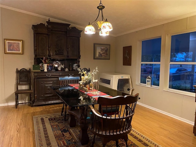 dining room featuring light wood-type flooring, crown molding, and a notable chandelier