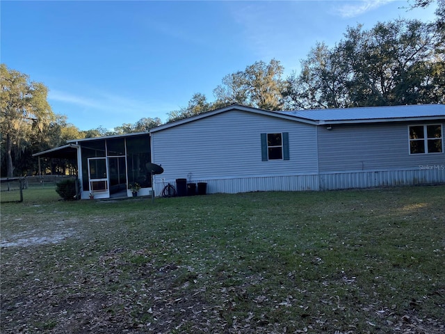 view of side of home with a sunroom and a yard