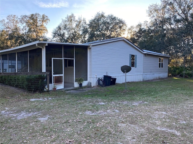 back of house featuring a sunroom and a lawn