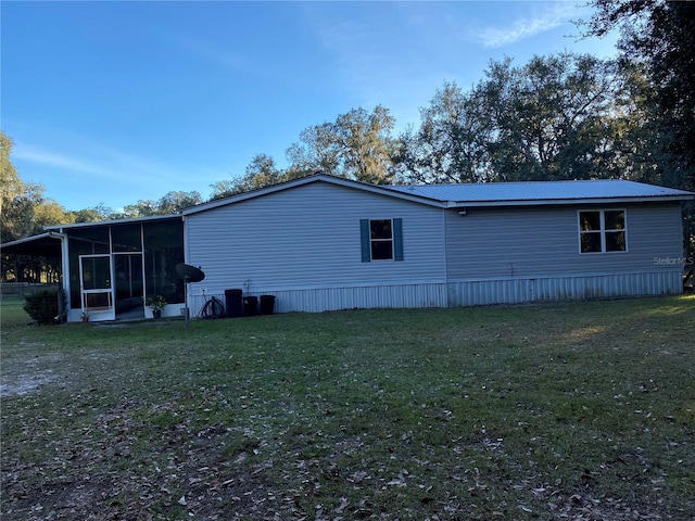 view of side of home with a sunroom and a lawn