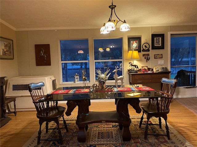 dining area featuring hardwood / wood-style floors, ornamental molding, and an inviting chandelier