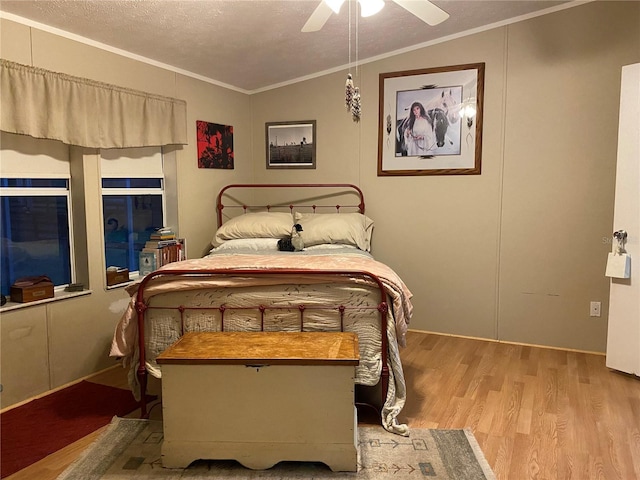 bedroom with ceiling fan, light hardwood / wood-style floors, a textured ceiling, vaulted ceiling, and ornamental molding