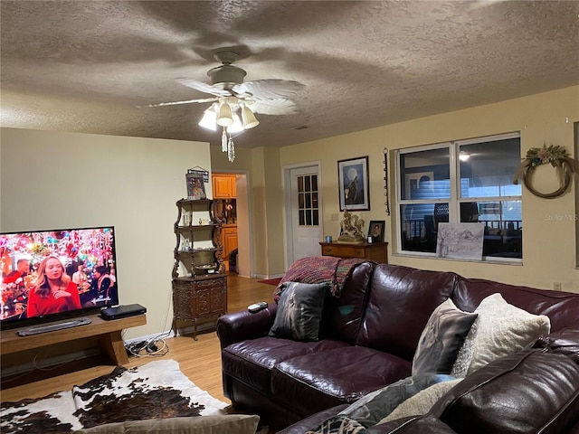 living room featuring ceiling fan, a textured ceiling, and light hardwood / wood-style flooring