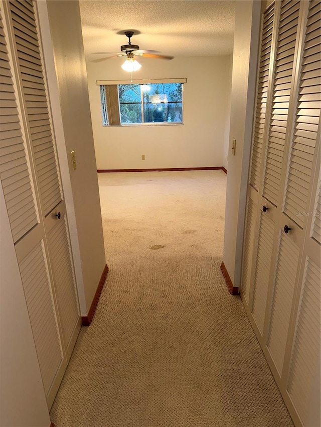 corridor featuring a textured ceiling and light carpet