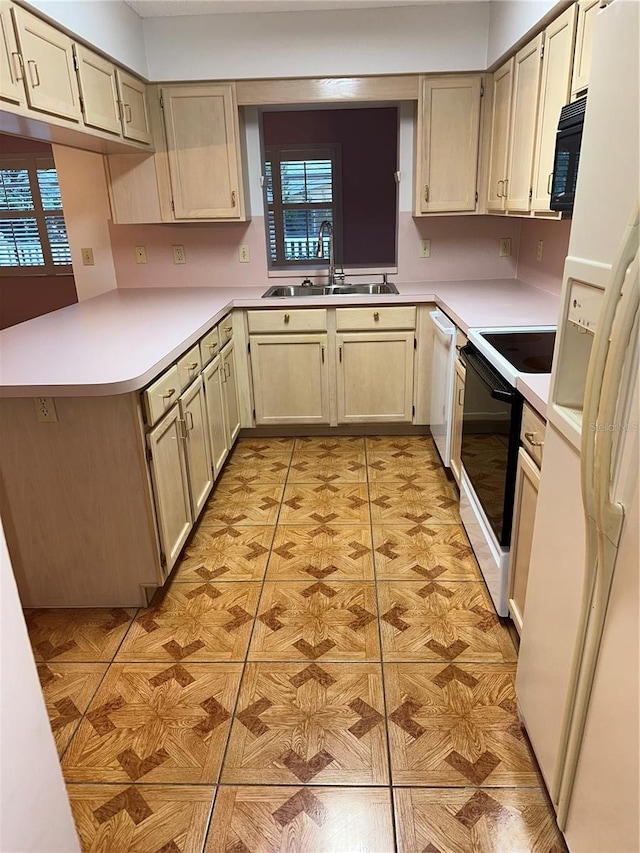 kitchen featuring sink, kitchen peninsula, white appliances, cream cabinetry, and light tile patterned floors