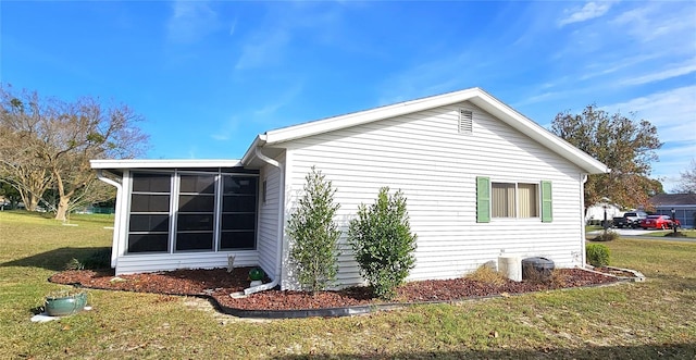 view of side of home featuring a lawn and a sunroom