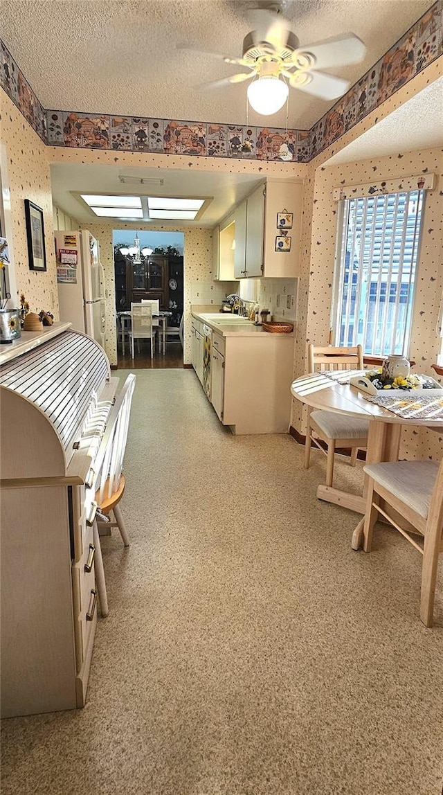 kitchen featuring a textured ceiling, white refrigerator, ceiling fan, and sink