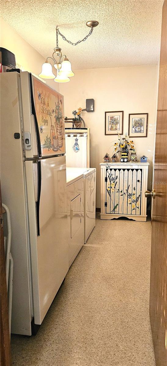 interior space featuring a textured ceiling, washer / dryer, a notable chandelier, and white refrigerator