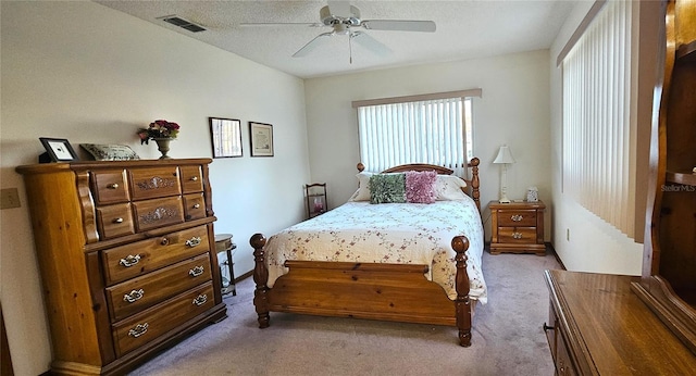 bedroom featuring ceiling fan, light carpet, and a textured ceiling