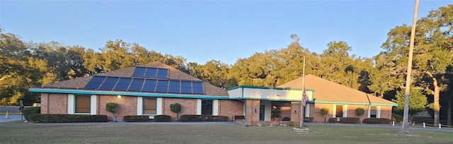 view of front facade featuring solar panels and a front lawn