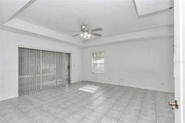 spare room featuring light tile patterned floors, a textured ceiling, a raised ceiling, and ceiling fan