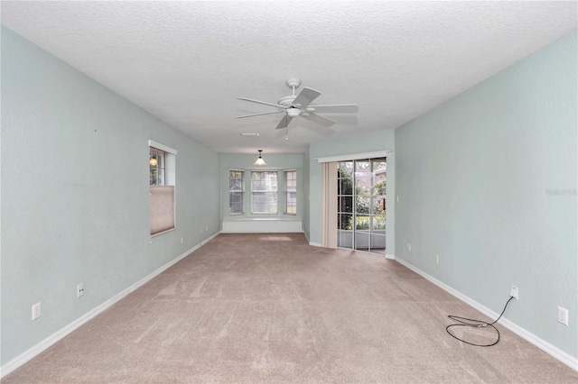 carpeted spare room with a textured ceiling, a wealth of natural light, and ceiling fan