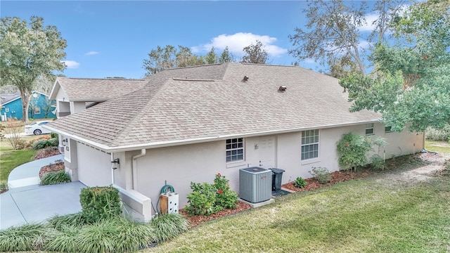 back of property featuring a garage, cooling unit, and a lawn