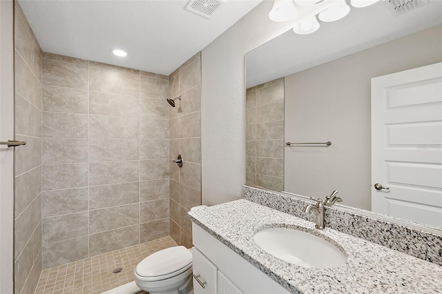 bathroom featuring a tile shower, vanity, and toilet