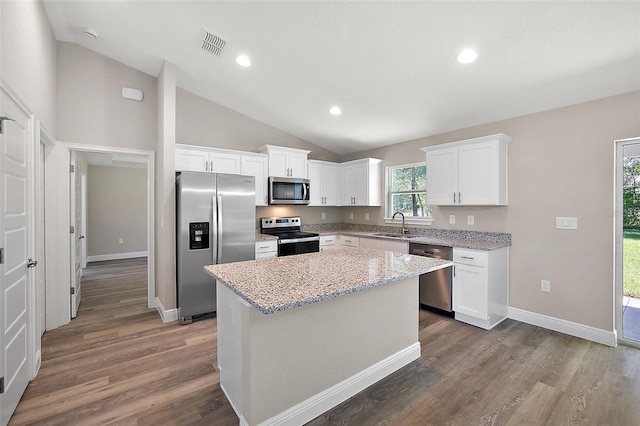 kitchen with a center island, sink, stainless steel appliances, vaulted ceiling, and white cabinets