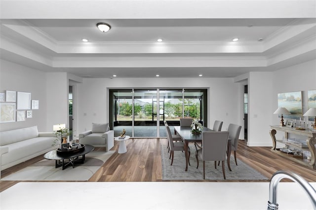 dining space featuring a tray ceiling, hardwood / wood-style floors, and ornamental molding