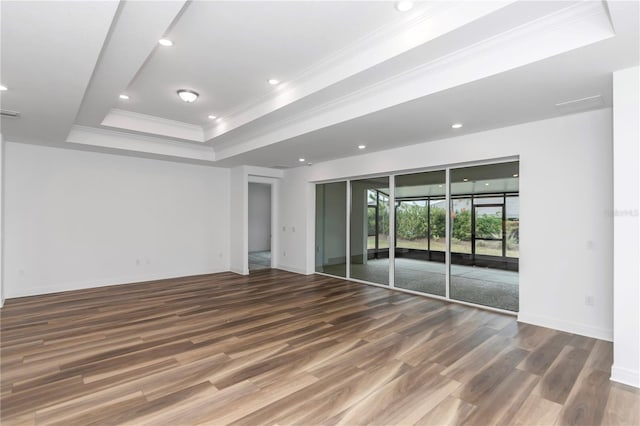 empty room featuring a tray ceiling, hardwood / wood-style floors, and ornamental molding