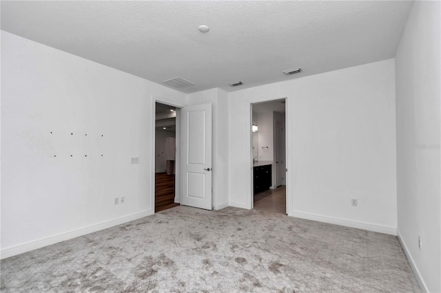 unfurnished bedroom featuring a textured ceiling and light colored carpet