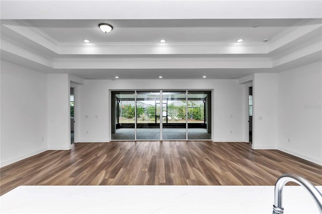 spare room featuring crown molding, dark wood-type flooring, and a tray ceiling