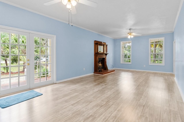 unfurnished living room with french doors, light wood-type flooring, crown molding, and a healthy amount of sunlight