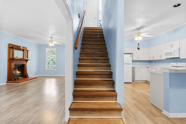 staircase with hardwood / wood-style flooring, ceiling fan, and crown molding