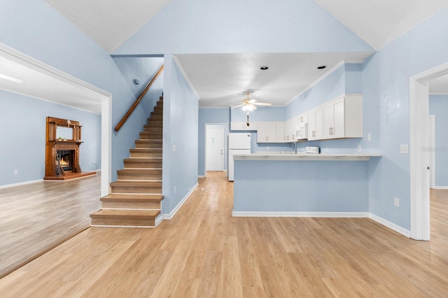 kitchen featuring white appliances, white cabinets, light hardwood / wood-style flooring, ceiling fan, and kitchen peninsula