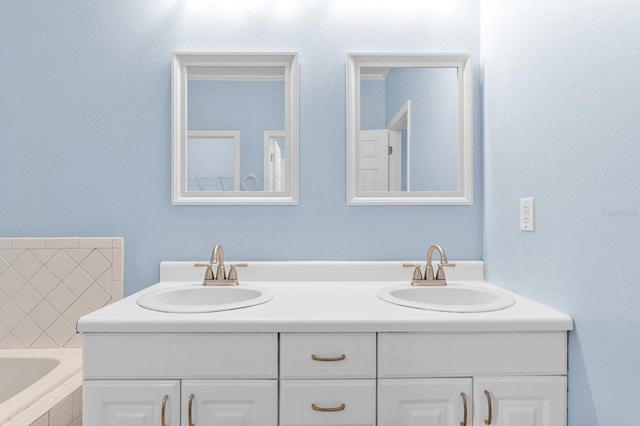 bathroom featuring tiled tub and vanity