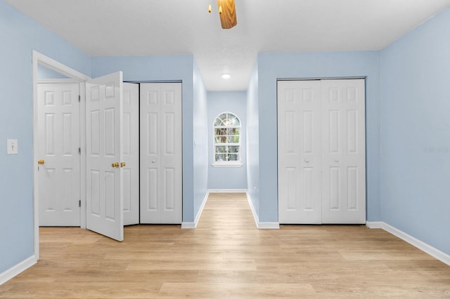 unfurnished bedroom with multiple closets, ceiling fan, and light hardwood / wood-style flooring