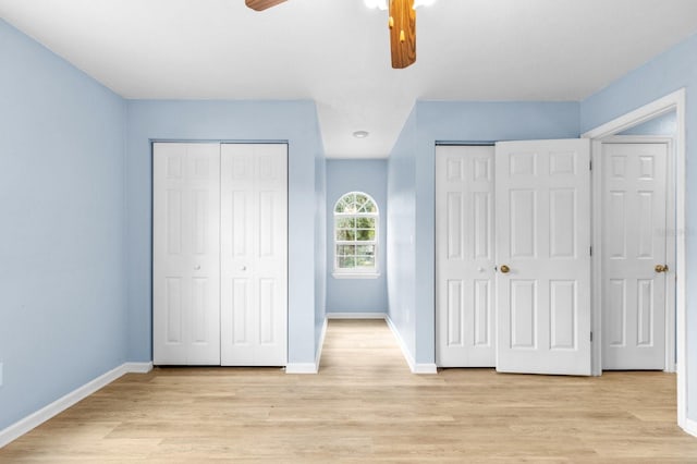 unfurnished bedroom with two closets, light hardwood / wood-style flooring, and ceiling fan