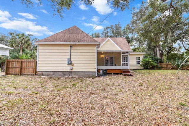 rear view of house with a sunroom, a yard, and central AC