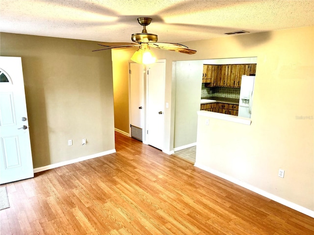 unfurnished living room featuring a textured ceiling, light hardwood / wood-style floors, and ceiling fan