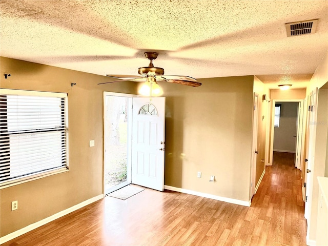 foyer entrance with ceiling fan, light hardwood / wood-style flooring, and a textured ceiling