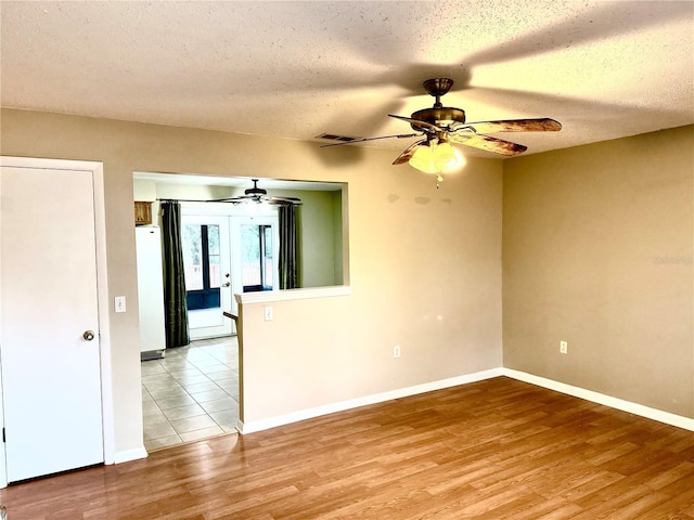 empty room with french doors, a textured ceiling, and light wood-type flooring