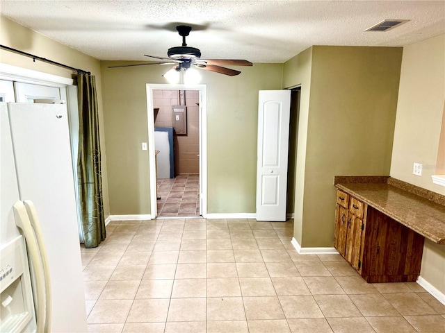 interior space with ceiling fan, white fridge with ice dispenser, a textured ceiling, and light tile patterned floors