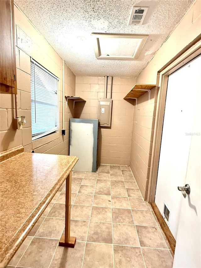 laundry room with light tile patterned flooring, a textured ceiling, and electric panel