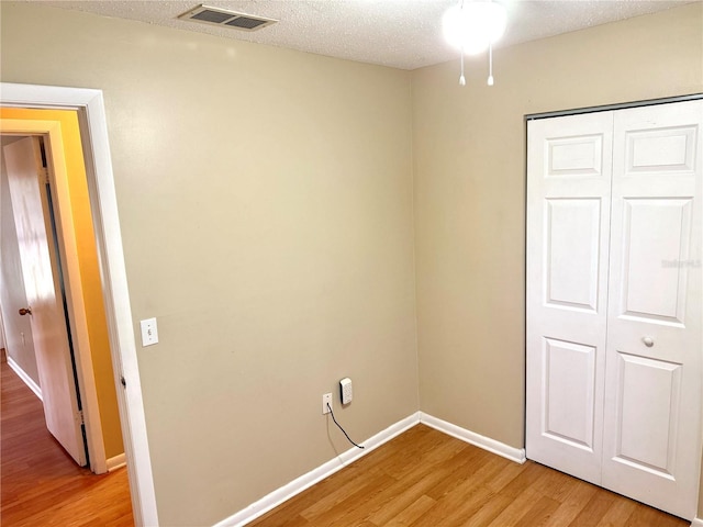 interior space with a closet, light hardwood / wood-style floors, and a textured ceiling