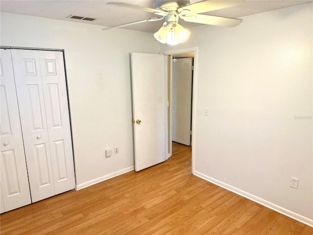 unfurnished bedroom with ceiling fan, a closet, and light wood-type flooring